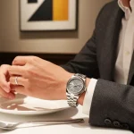 Elegant individual displaying a detailed rolex replica watch in a sophisticated dining setting.